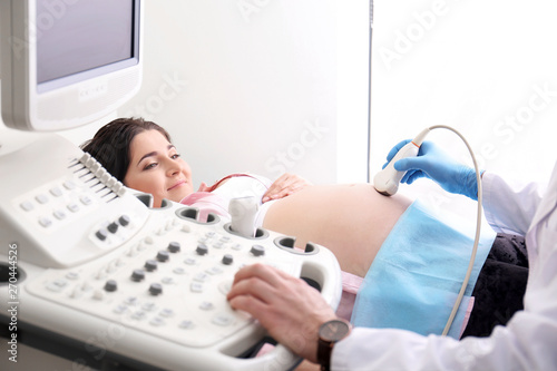 Young pregnant woman undergoing ultrasound scan in clinic