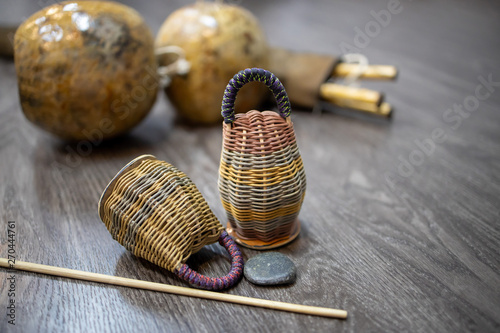 Photos close-up on caxixi dobrao with berimbau on the wooden floor