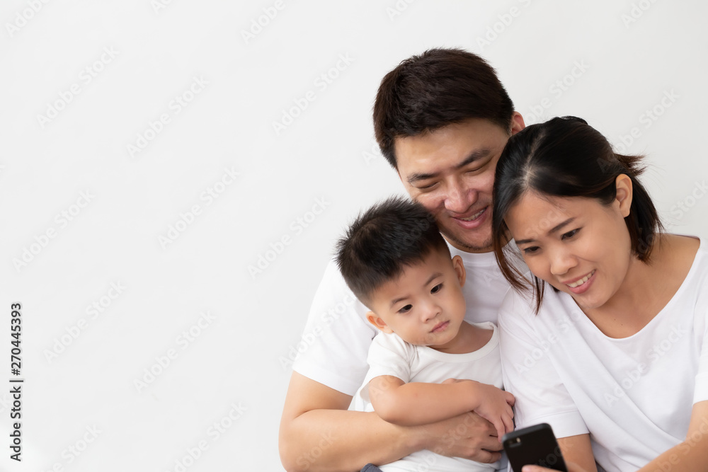 Cheerful young Asian family with son laughing watching funny video on smartphone, Parents with children enjoy playing games or entertaining using mobile application