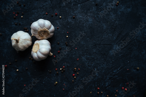 Three whole garlic bulbs isolated on black stone table background. Flat lay. Top view. Food concept. Space for text