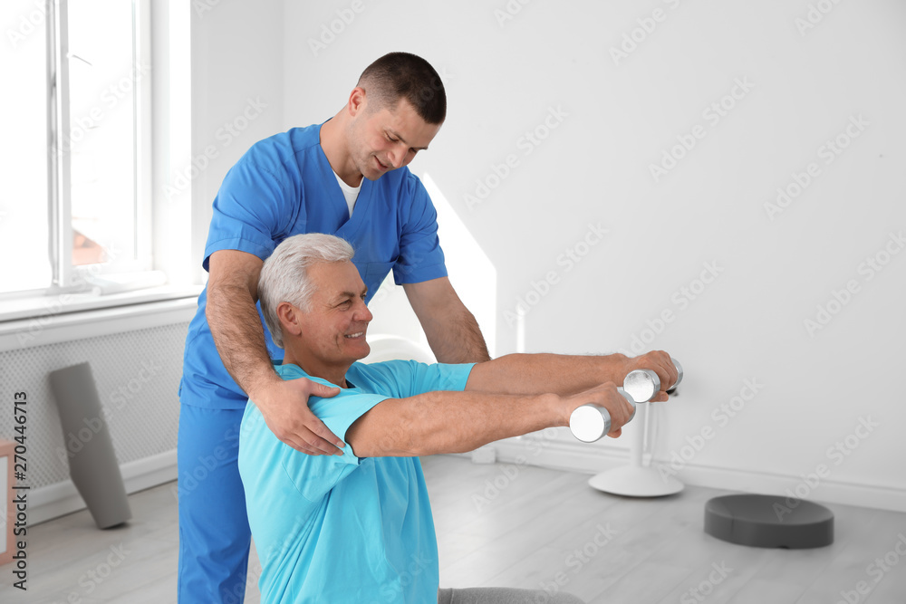 Obraz premium Professional physiotherapist working with senior patient in rehabilitation center