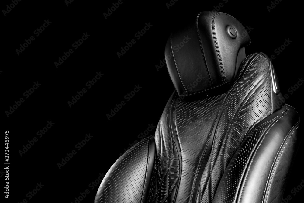 Black leather interior of the luxury modern car. Perforated leather comfortable seats with stitching isolated on black background. Modern car interior details. Car detailing. Black and white