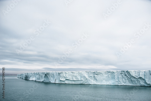 фотографія Dramatic wide angle view along an arctic glacier wall with calm sea