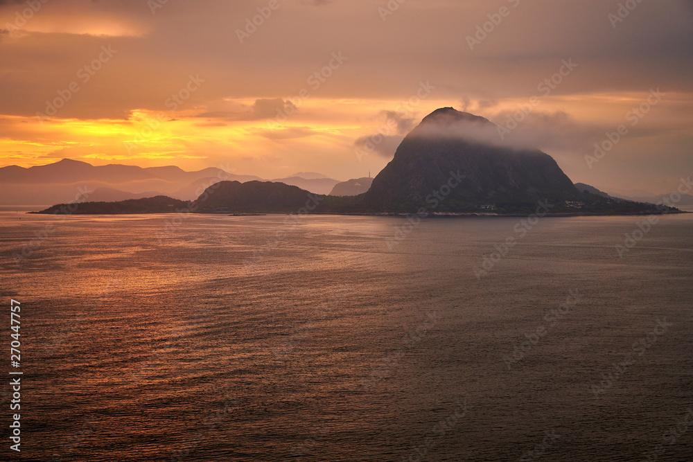 Rock in the ocean with clouds in sunrise