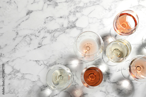 Different glasses with wine on marble background, flat lay. Space for text