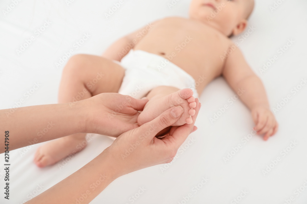 Mother and her cute child on white bed, closeup. Baby massage and exercises Mother and her cute child on white bed, closeup. Baby massage and exercises