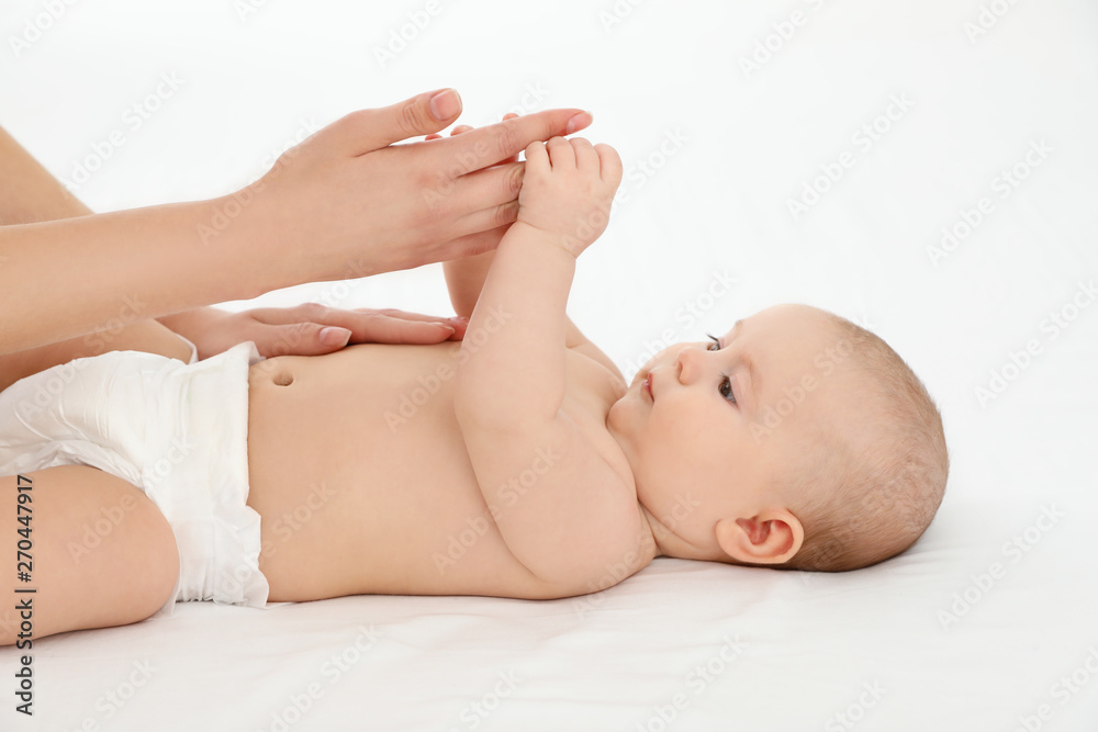 Mother and her cute child on white bed. Baby massage and exercises Mother and her cute child on white bed. Baby massage and exercises