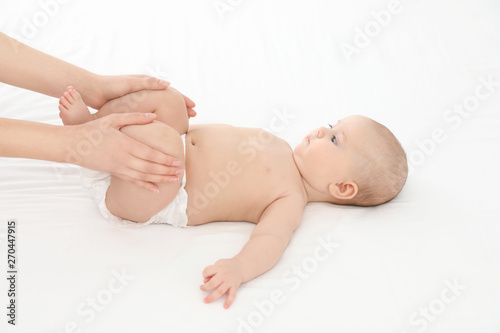 Mother and her cute child on white bed. Baby massage and exercises