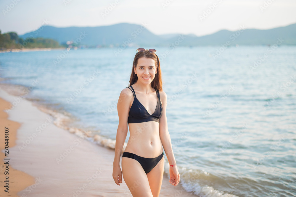 Beautiful woman in black bikini is relaxing on the beach, summer concept Beautiful woman in black bikini is relaxing on the beach, summer concept