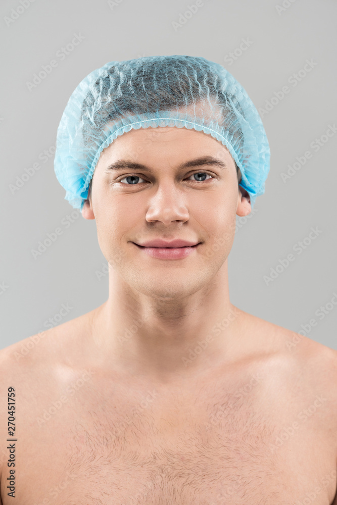 front view of smiling naked young man in medical cap isolated on grey front view of smiling naked young man in medical cap isolated on grey