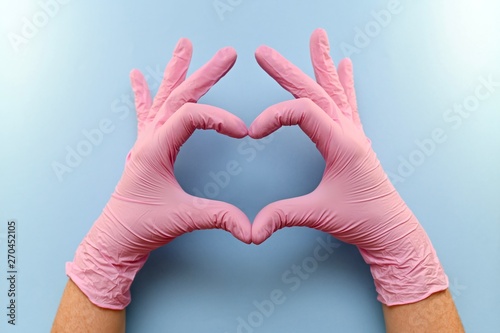 The heart, figure built from the hands in pink rubber medical gloves on a blue background.