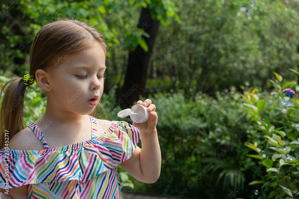 Cute little girl is blowing a soap bubbles in the garden Cute little girl is blowing a soap bubbles in the garden