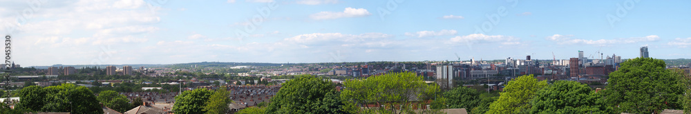 a wide panoramic view showing the leeds city center and surrounding districts with towers apartments roads and commercial buildings against a blue sky a wide panoramic view showing the leeds city center and surrounding districts with towers apartments roads and commercial buildings against a blue sky