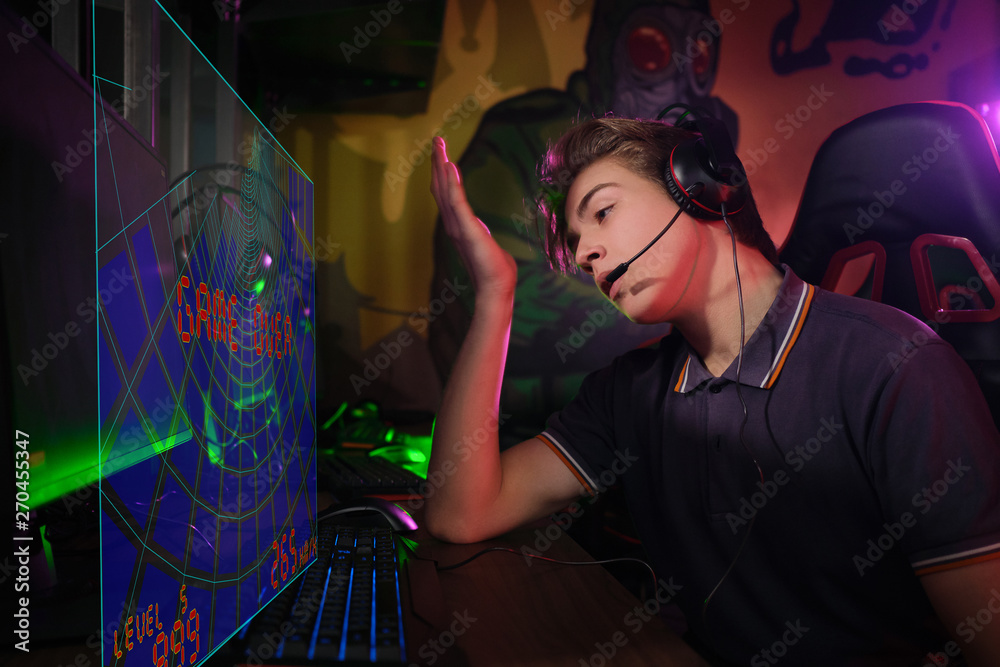 Professional young caucasian gamer playing online on his PC. He upset because of losing the game Professional young caucasian gamer playing online on his PC. He upset because of losing the game