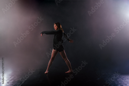 Shoeless female dance shows off her modern art dance moves while looking serious and devoted.
