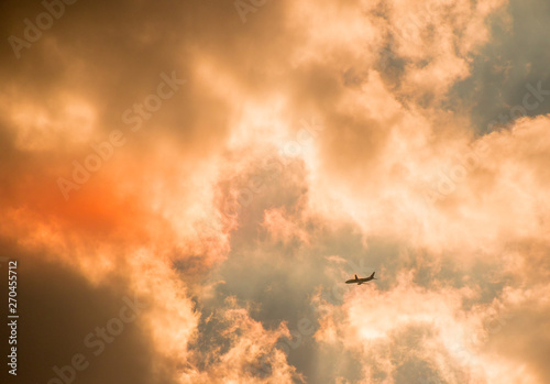 An jet airliner flies into a fiery cloudbank at sunset image in landscape format with copy space