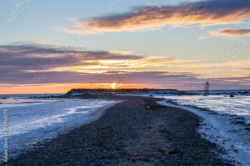 Sunset over long peninsula in shallow Baltic sea, frosty winter time. Path to the sun.