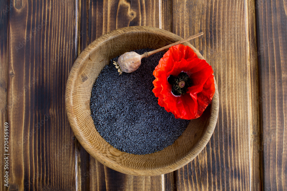 Poppy seeds in the brown bowl in the center of the wooden background.Top view.Copy space Poppy seeds in the brown bowl in the center of the wooden background.Top view.Copy space