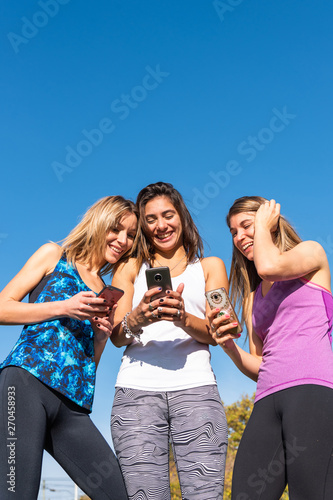 Three happy young women watching the smart phone with a blue sky