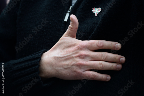 hand on the chest next to a pin with the relief of Euskaleherria and the colors of the Basque Country, Spain
