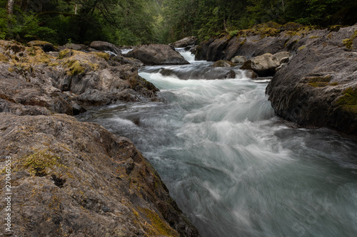 A fast flowing river runs over pebbles and rocks in Olympic National Park  Washington State  USA  long exposure to add blurred motion to the  water  nobody in the image
