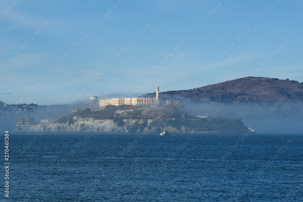 SAN FRANCISCO, CALIFORNIA, UNITED STATES - NOV 25th, 2018: Alcatraz prison in fog panorama during a sunny day in November as seen from pier 39