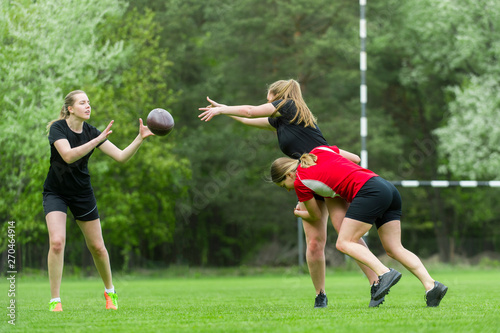 Girls playing american football together outside in summer