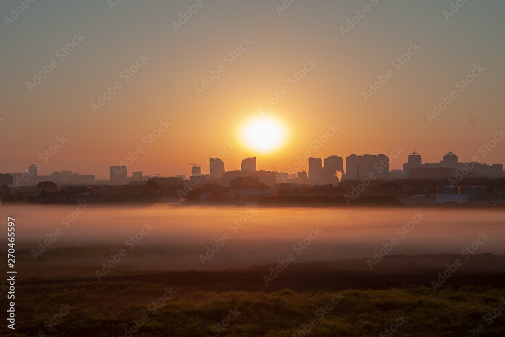 The dawn in the countryside with the thick fog on the field, with the backdrop of the tower of the big city. Time lapse of the rising of the sun and the disappearance of the fog