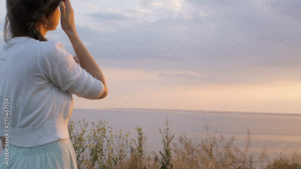 young woman looking at the sunset, the girl walking on nature on a warm evening and enjoying beautiful sky, the concept of nature and health care young woman looking at the sunset, the girl walking on nature on a warm evening and enjoying beautiful sky, the concept of nature and health care