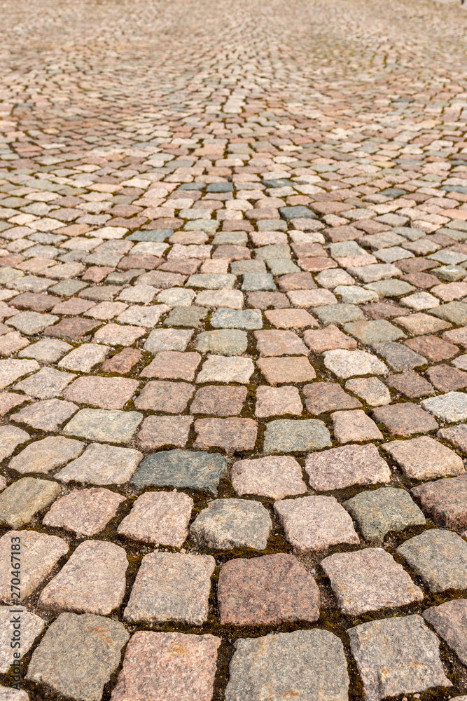 A fragment of the sidewalk, lined with colored granite stone in the town square.  Texture, background.