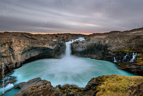 Aldeyjarfoss waterfall in Iceland at sunrise with golden clouds in the sky. Amazing landscape in beautiful tourist attraction. Wonder of nature with glacier water. © aroxopt