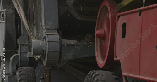 A historic farming machine with fast rotating wheels and belt drives.