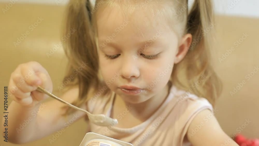 little girl with pigtails eating yogurt, useful dairy products for baby food little girl with pigtails eating yogurt, useful dairy products for baby food