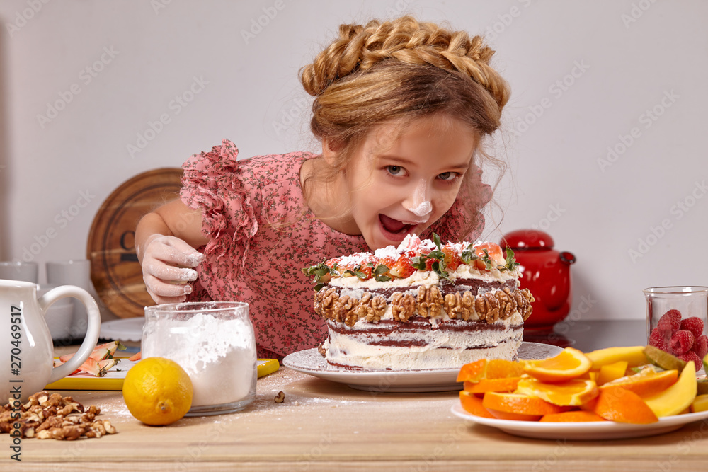 Little girl is making a homemade cake with an easy recipe at kitchen against a white wall with shelves on it. Little girl is making a homemade cake with an easy recipe at kitchen against a white wall with shelves on it.