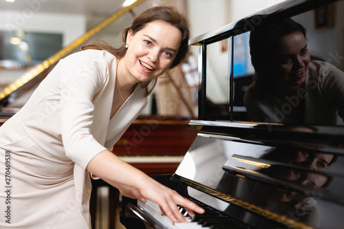 Beautiful girl chooses a piano in a music store