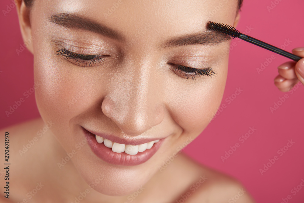 Beautician shaping young lady eyebrows with brush