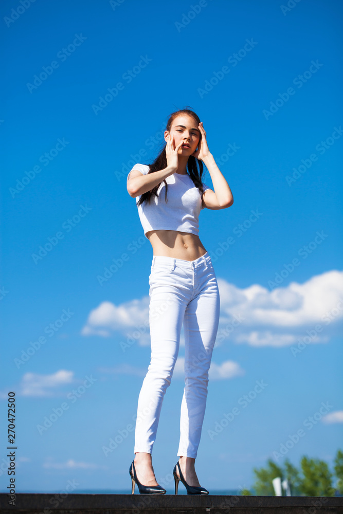 Beautiful brunette woman posing against blue sky bright sunny weather Beautiful brunette woman posing against blue sky bright sunny weather
