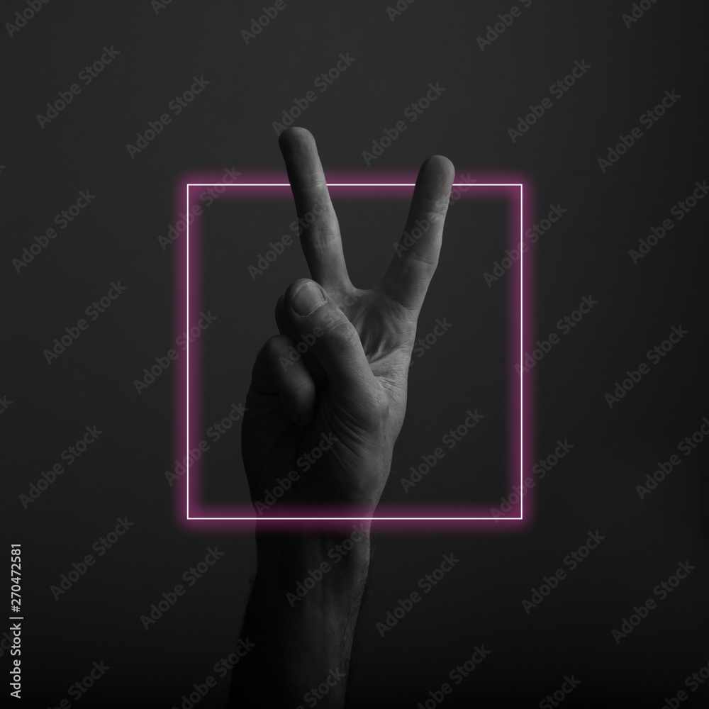 Male hand showing victory V hand sign with abstract neon light glow Male hand showing victory V hand sign with abstract neon light glow