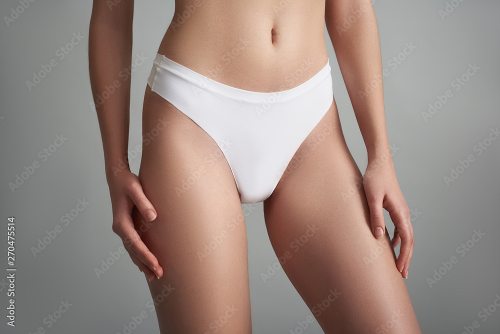 Slim woman in panties isolated on grey background