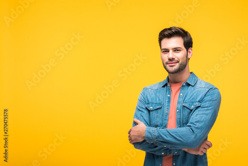 happy handsome man with crossed arms looking at camera Isolated On yellow © LIGHTFIELD STUDIOS