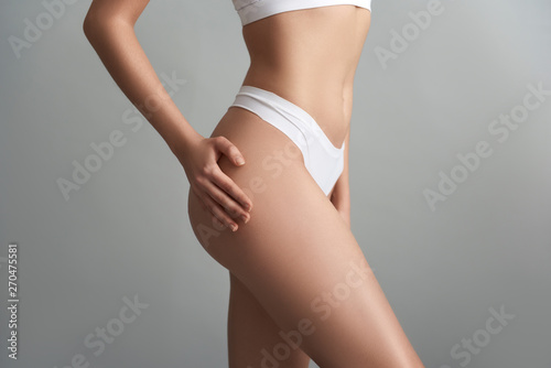 Slim woman in white underwear isolated on grey background