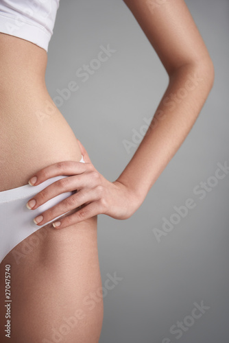 Young woman in underwear against grey background