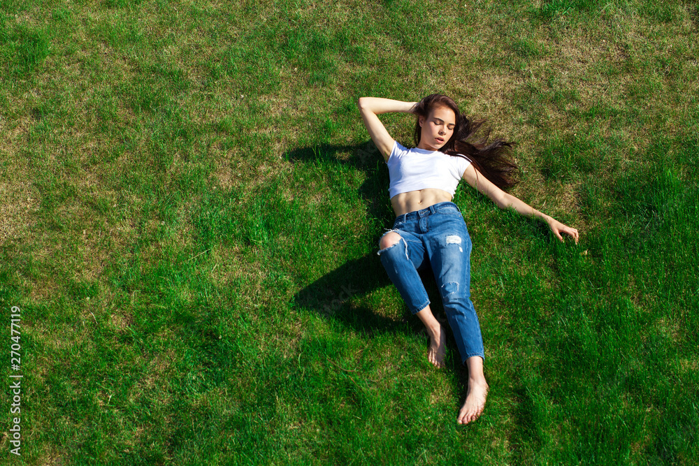 Portrait of a young beautiful girl resting on the lawn in the park Portrait of a young beautiful girl resting on the lawn in the park