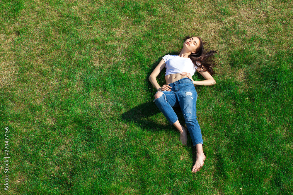 Portrait of a young beautiful girl resting on the lawn in the park Portrait of a young beautiful girl resting on the lawn in the park