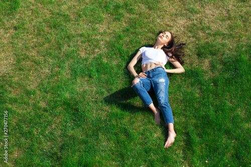 Portrait of a young beautiful girl resting on the lawn in the park