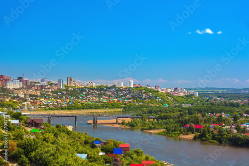 White River in the city center on the background of private houses with colorful roofs on a slope with green trees and modern high-rise buildings. Belsky Bridge, Ufa, Bashkortostan, Russia. photo