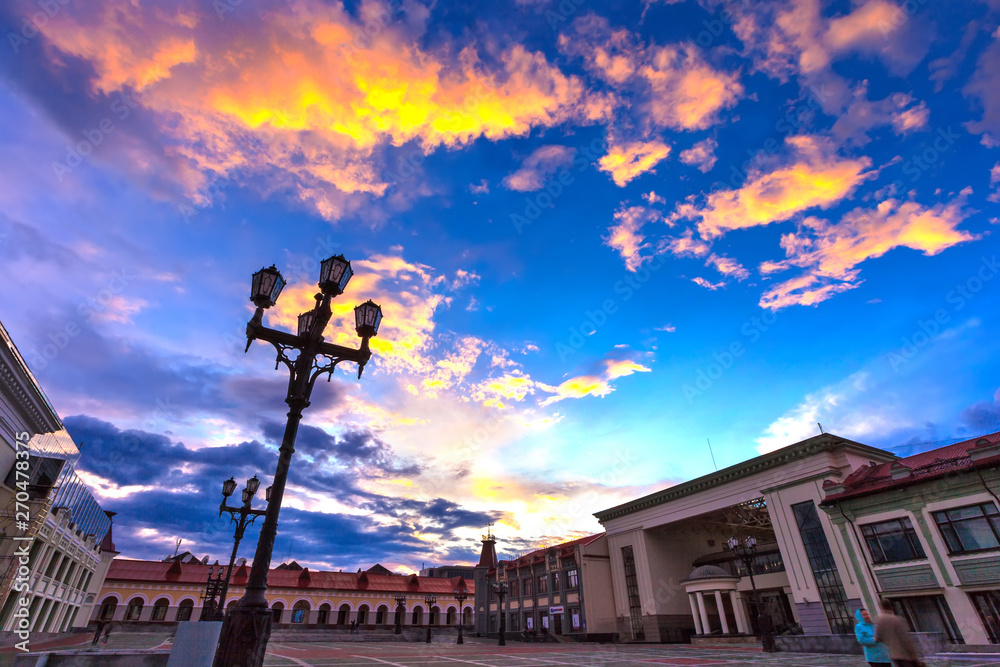 The central city square with beautiful modern architecture for the rest of the locals under a blue sky with colorful clouds. Gostiny Dvor square, Lenina street, Ufa, Bashkortostan, Russia - June 2015.