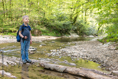 Boy traveler crosses the creek on a log