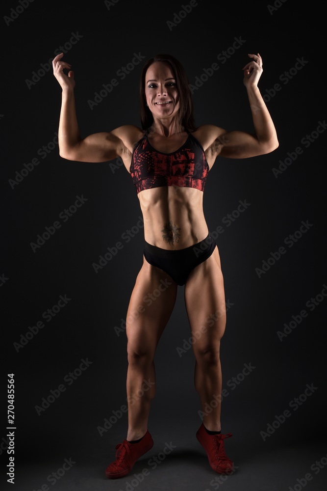 Sporty woman does the exercises on black background