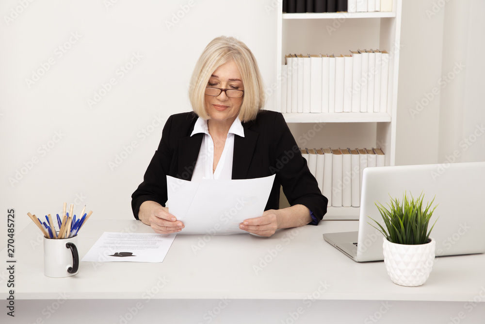 Elegant adult office worker in eyeglassess working with paper indoor Elegant adult office worker in eyeglassess working with paper indoor